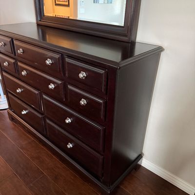 Sale Photo Thumbnail #17: Dark mahogany wood dresser featuring nine drawers with silver-tone hardware and an attached matching wall mirror.