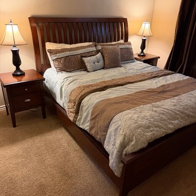 Sale Photo Thumbnail #130: Contemporary dark wood queen bed frame with slatted headboard, flanked by matching two-drawer nightstands and dark table lamps.