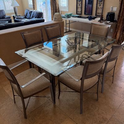 Sale Photo Thumbnail #210: Modern dining set featuring a large glass-top table with a metal frame and six upholstered metal-framed dining chairs.