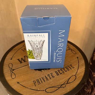 Sale Photo Thumbnail #26: Marquis by Waterford 9-inch clear crystal vase in original Rainfall Collection box, resting on a round wooden table.