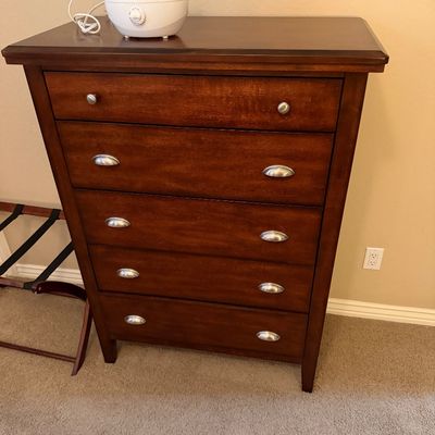 Sale Photo Thumbnail #139: Contemporary five-drawer wooden dresser in a warm cherry finish with brushed nickel bin pulls, topped with a small blue ultrasonic humidifier.
