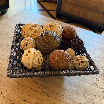 Sale Photo Thumbnail #52: Dark woven basket filled with an assortment of decorative spheres made from natural fibers, rattan, and carved resin.