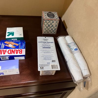 Sale Photo Thumbnail #141: Selection of household and personal care items, including Band-Aid bandages, Up&Up gauze pads, Equate cotton swabs, Kirkland facial tissue, and small bathroom paper cups.