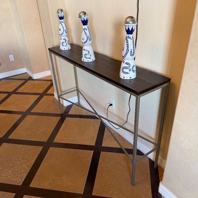 Sale Photo Thumbnail #28: Contemporary narrow sofa or console table featuring a dark wood top and silver metal frame, topped with three decorative Clase Azul tequila bottles.