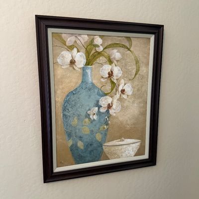 Sale Photo Thumbnail #113: Framed floral still life wall art depicting white orchids in a blue vase, signed by the artist in the lower left corner.