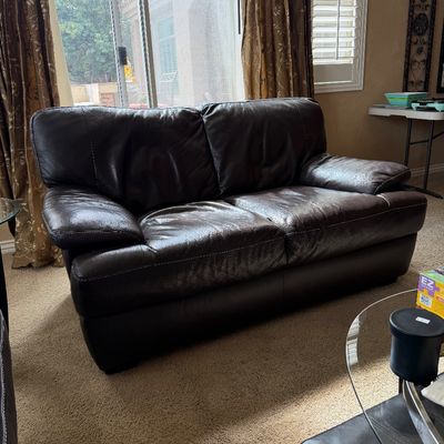 Sale Photo Thumbnail #2: Contemporary dark brown leather loveseat with pillow-top armrests and white contrast stitching.