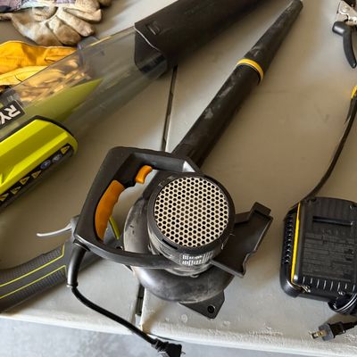Sale Photo Thumbnail #80: Assorted power yard tools including a corded leaf blower, Ryobi vacuum attachment, battery charger, and work gloves.