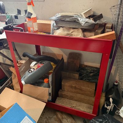 Sale Photo Thumbnail #163: Two-tier red steel utility cart loaded with workshop supplies, lumber scraps, automotive fluids, and spray bottles.