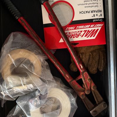 Sale Photo Thumbnail #147: A tool drawer containing a pair of heavy-duty bolt cutters with red handles, rolls of tape, a leather work glove, and a Wal-Board drywall repair patch.
