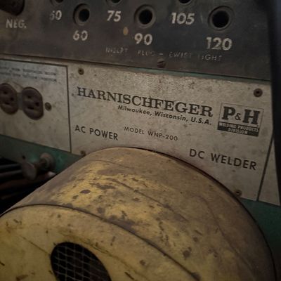 Sale Photo Thumbnail #156: Vintage Harnischfeger P&H Model WNP-200 AC power DC welder featuring amperage setting ports and a weathered metallic casing.
