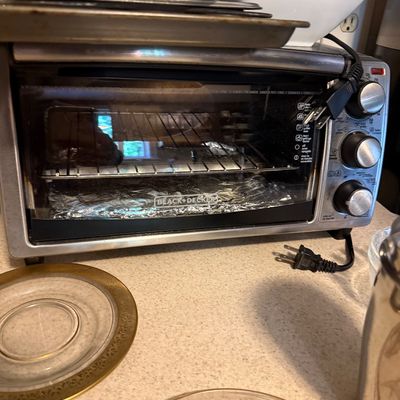 Sale Photo Thumbnail #57: Black + Decker countertop toaster oven with stainless steel housing and analog dial controls.