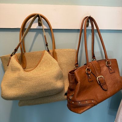 Sale Photo Thumbnail #106: Trio of women's handbags hanging on hooks, including woven straw shoulder bags and a tan leather tote with brass hardware details.