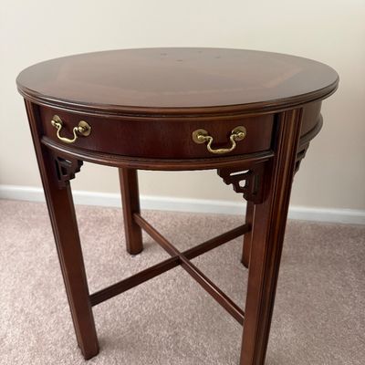 Sale Photo Thumbnail #77: Traditional mahogany round side table featuring brass drawer pulls, carved corner brackets, and an X-frame stretcher base.
