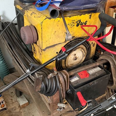 Sale Photo Thumbnail #158: Vintage yellow The Bug portable welder unit with attached cables, battery, and a Sanyo boombox stored on top.