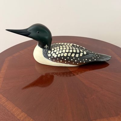 Sale Photo Thumbnail #42: Hand-painted wooden loon decoy figurine with detailed feather patterns, resting on a polished wood surface.