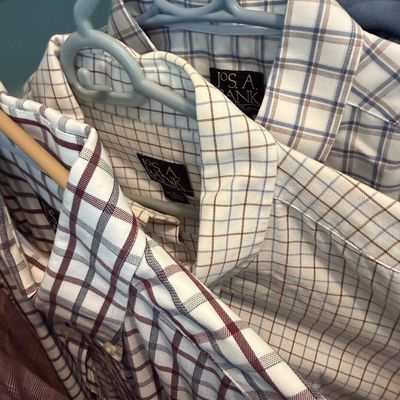 Sale Photo Thumbnail #96: Selection of men's long-sleeve plaid button-up shirts by JoS. A. Bank, hanging on plastic hangers in good pre-owned condition.