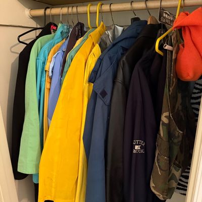 Sale Photo Thumbnail #126: Selection of vintage and contemporary outerwear hanging in a closet, including a yellow raincoat, Cutter & Buck jacket, camouflage hunting vest, and brightly colored windbreakers.