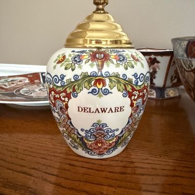 Sale Photo Thumbnail #71: Vintage small ceramic apothecary jar labeled "DELAWARE" with ornate multicolor floral transfers and a tiered gold-tone metal lid.