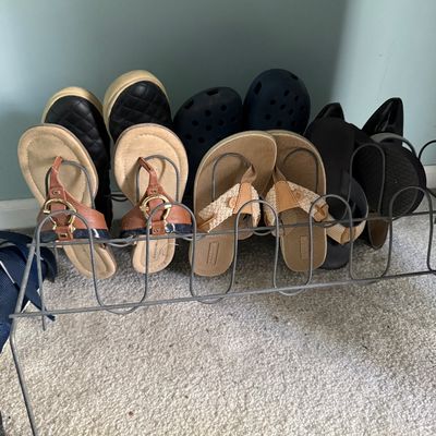 Sale Photo Thumbnail #89: Wire metal shoe rack holding multiple pairs of women's shoes, including sandals, slip-ons, and clogs.