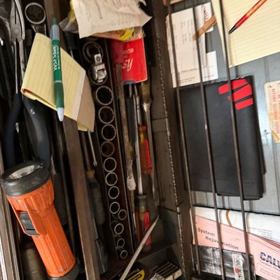Sale Photo Thumbnail #133: Vintage metal toolbox filled with various hand tools, including an orange flashlight, socket set, screwdrivers, tape measure, and assorted hardware supplies.