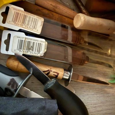 Sale Photo Thumbnail #58: Collection of assorted oyster shucking knives, including new-in-package walnut-handled bent knives and various wooden and rubber-handled styles.