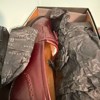 Sale Photo Thumbnail #101: Burgundy leather wingtip tassel loafers stored in their original box with tissue paper.