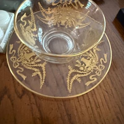 Sale Photo Thumbnail #14: Vintage clear glass bowl and matching saucer set, featuring elaborate gold-encrusted floral, urn, and ribbon bow motifs with gold rims.
