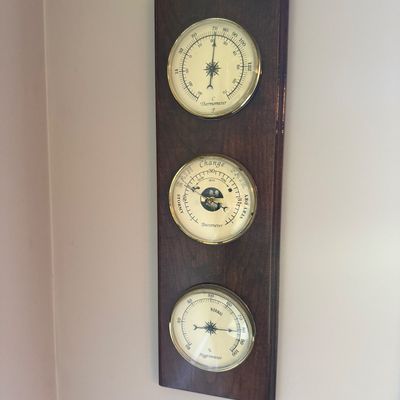 Sale Photo Thumbnail #65: Vintage wall-mounted weather station featuring a thermometer, barometer, and hygrometer with brass bezels set on a dark wood plaque.