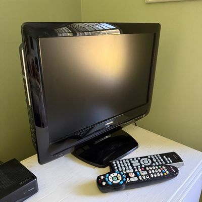 Sale Photo Thumbnail #120: Black Toshiba flat-screen LCD television with integrated DVD player, displayed on a tabletop alongside two remote controls.