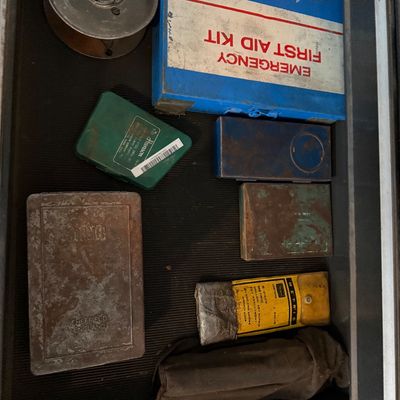 Sale Photo Thumbnail #149: Assorted vintage tools and supplies inside a toolbox drawer, including a vintage Johnson & Johnson metal emergency first aid kit, drill bit cases, and a wire spool.