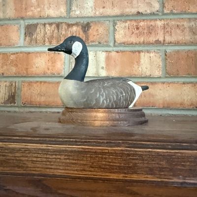 Sale Photo Thumbnail #41: Hand-carved and painted wooden Canada goose decoy displayed on an oval wooden base.