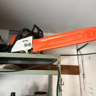 Sale Photo Thumbnail #162: Stihl gas-powered chainsaw with an orange protective blade sheath