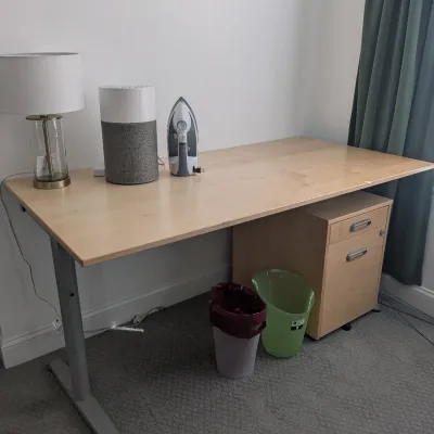 Modern light wood veneer office desk with grey metal legs, accompanied by a matching two-drawer mobile filing cabinet.