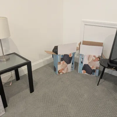 Collection of household items including a Pelonis tower space heater, modern end tables, a brushed metal lamp, and boxed Intex air...