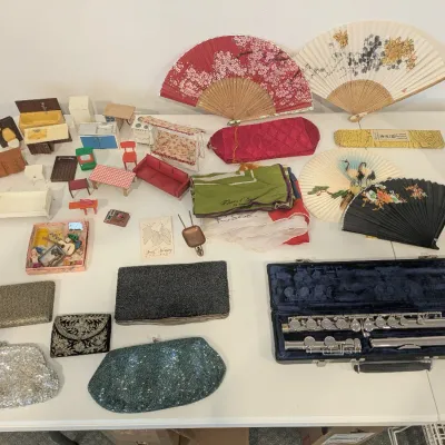 Collection of vintage items including a silver-tone flute in its original hard case, beaded clutches, decorative Asian folding fans, and...