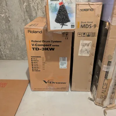 Roland V-Compact Series TD-3KW electronic drum set and MDS-9 drum stand in original manufacturer boxes, paired with an artificial tree box.