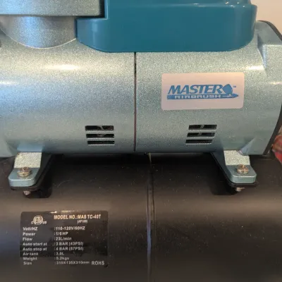 Master Airbrush model MAS TC-40T air compressor mounted on a black air storage tank, featuring an attached moisture trap and pressure...