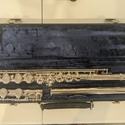 Silver-plated closed-hole flute resting inside a navy blue plush-lined hard protective case.