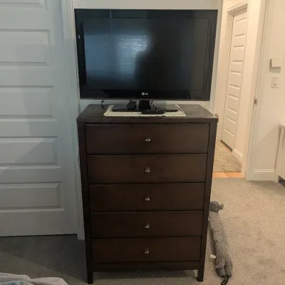 Dark espresso five-drawer chest of drawers with simple metal knobs, topped with a black LG flat-screen television.