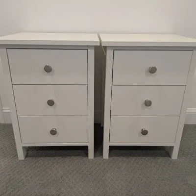 Pair of modern white three-drawer nightstands featuring simple brushed metal round knobs.