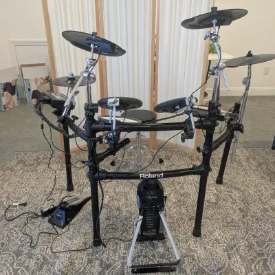 Roland V-Drums electronic drum kit featuring rubber drum pads, cymbal pads, kick trigger pedal, hi-hat control pedal, and sound module...