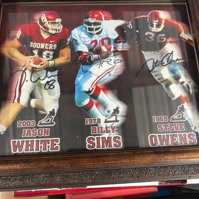 Sale Photo Thumbnail #130: Framed autographed photo display featuring Oklahoma Sooners Heisman Trophy winners Jason White, Billy Sims, and Steve Owens.