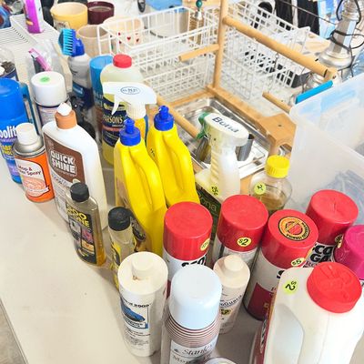Sale Photo Thumbnail #22: Assortment of household cleaning supplies, floor polishers, and fabric sprays arranged on a folding table.
