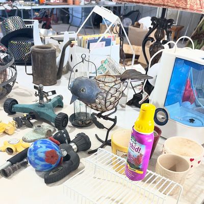 Sale Photo Thumbnail #23: Assortment of household goods, lawn sprinklers, a Vicks humidifier, decorative bird figurines, and ceramic pots on a table.