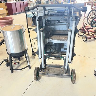 Sale Photo Thumbnail #5: Metabo HPT portable jobsite table saw on a rolling folding stand, shown next to an outdoor propane turkey fryer pot setup.