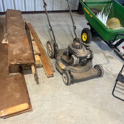 Sale Photo Thumbnail #127: Gas-powered push lawn mower with Briggs & Stratton engine, showing heavy wear and surface dirt.