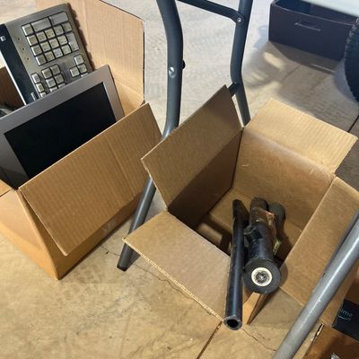 Sale Photo Thumbnail #38: Cardboard boxes containing assorted items, including a computer keyboard and small monitor on the left, and automotive or mechanical parts on the right.