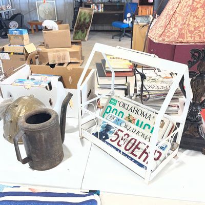 Sale Photo Thumbnail #68: Rustic metal watering can, novelty helmet, and a white wire house-shaped magazine rack containing vintage Oklahoma license plates.