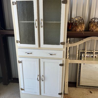 Sale Photo Thumbnail #73: Vintage white painted wooden hutch featuring textured glass upper cabinet doors, a central drawer, and solid lower cabinet doors.
