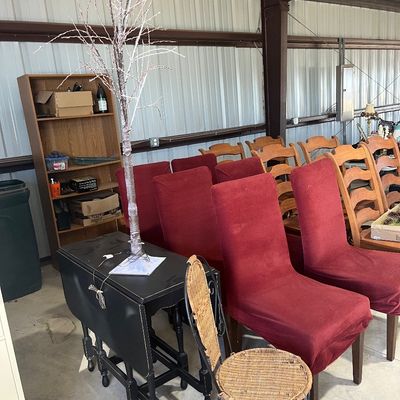 Sale Photo Thumbnail #129: Collection of dining furniture including red slipcovered high-back chairs, wooden ladderback chairs, a black drop-leaf side table, and a metal-and-wicker side chair.